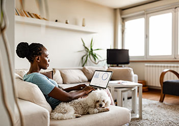 Woman sitting on her couch, using her laptop